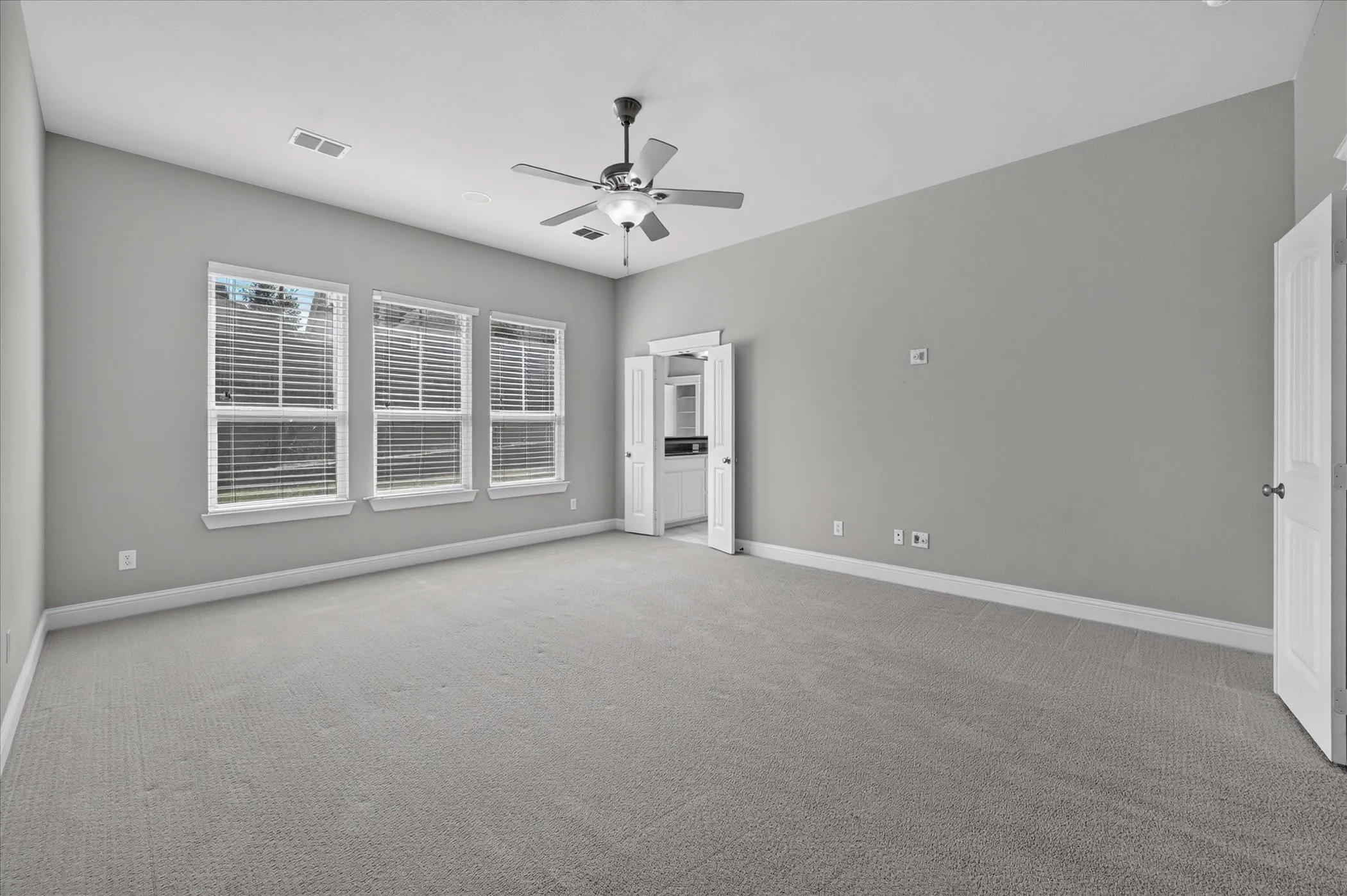 Vaulted ceiling, ceiling fan, grey wall paint, grey carpeting, multiple windows