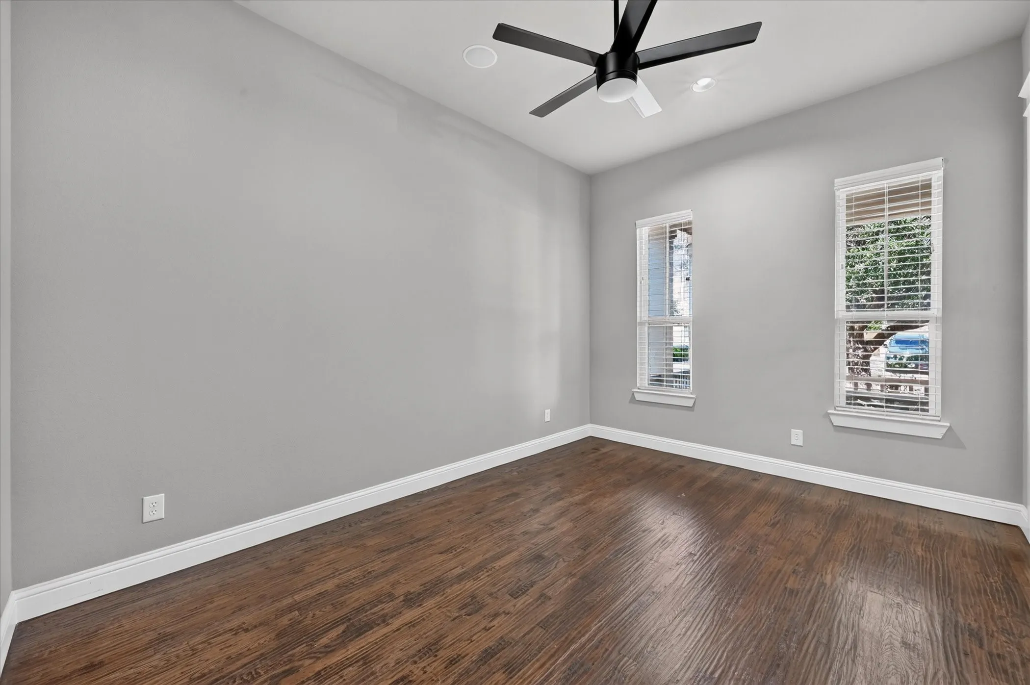 Wood-finish flooring, recessed lighting, ceiling fan, and white trim accents