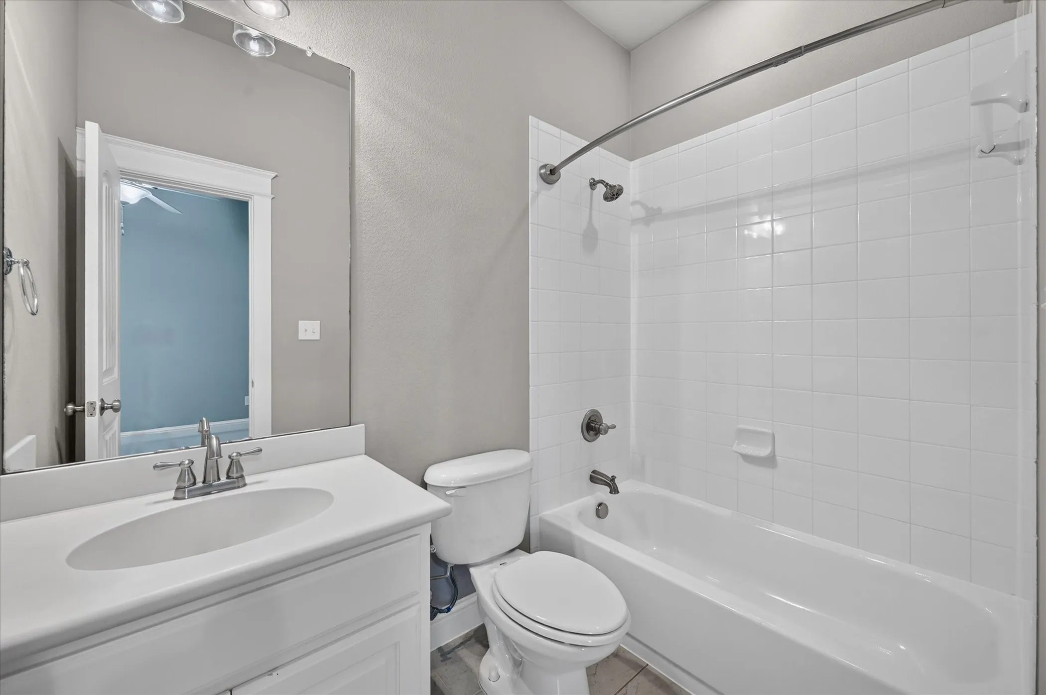 Full bathroom featuring a single vanity, a toilet, and a combination tub/shower with white tile surround