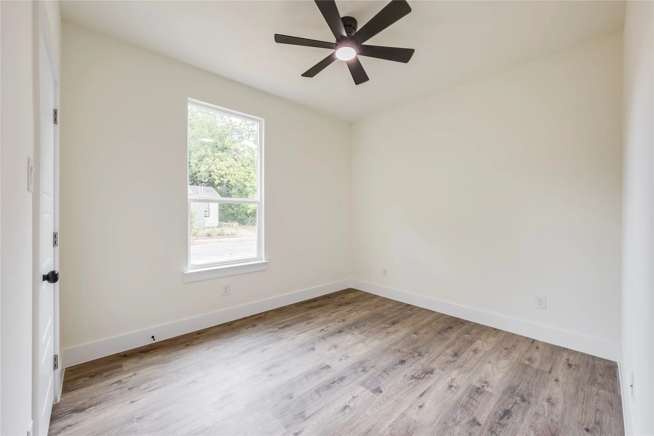Wood-finish flooring, white walls, and a ceiling fan with integrated lighting