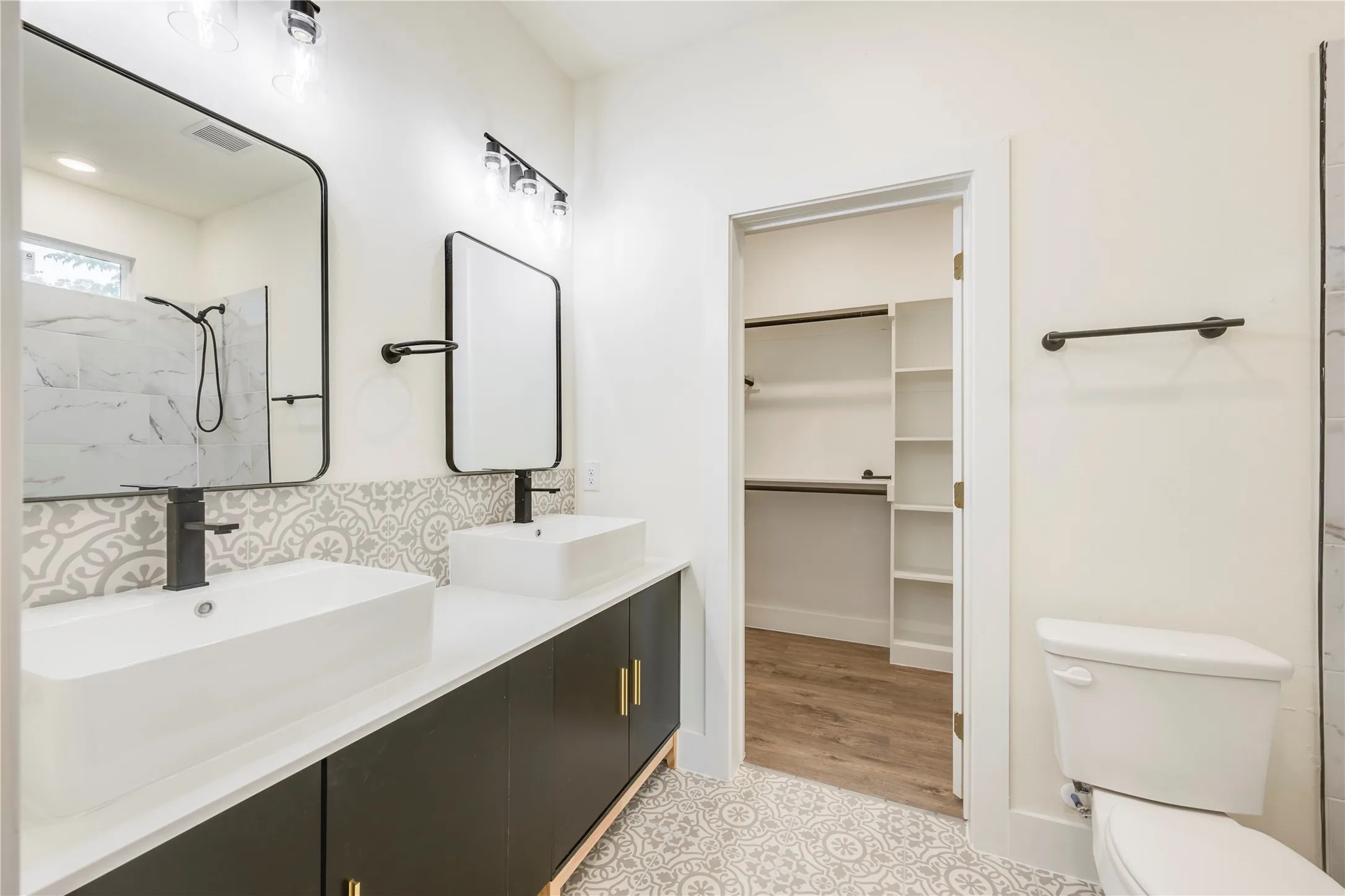 Double vanity with vessel sinks, matte black fixtures, and patterned floor tile