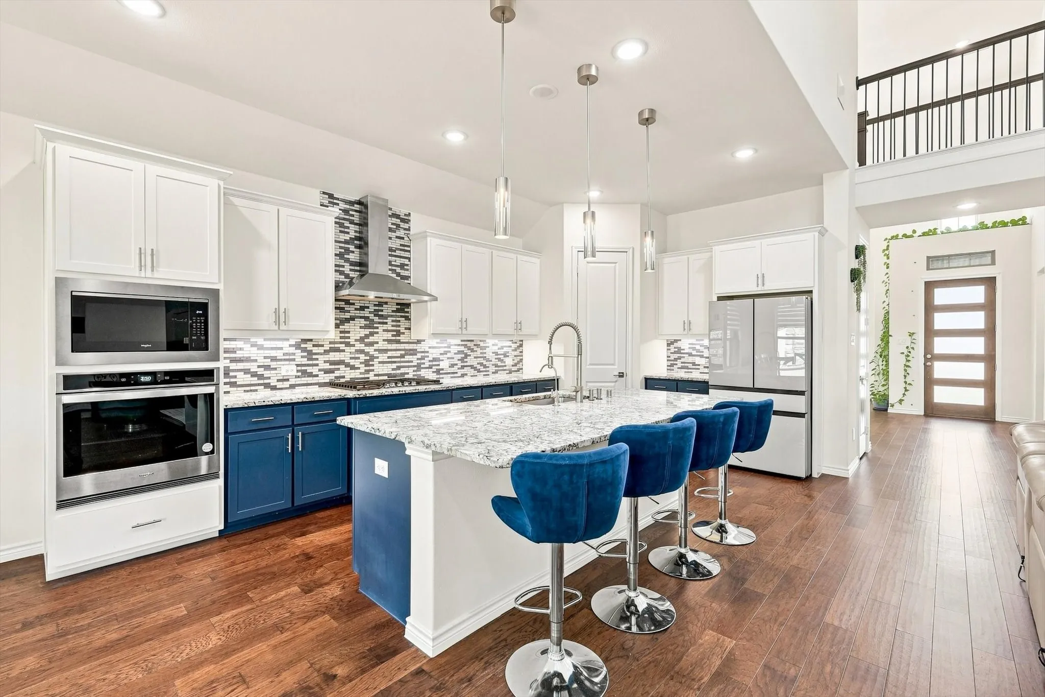 Gourmet kitchen with stainless steel appliances, two-tone cabinetry, a mosaic tile backsplash, and a large central island