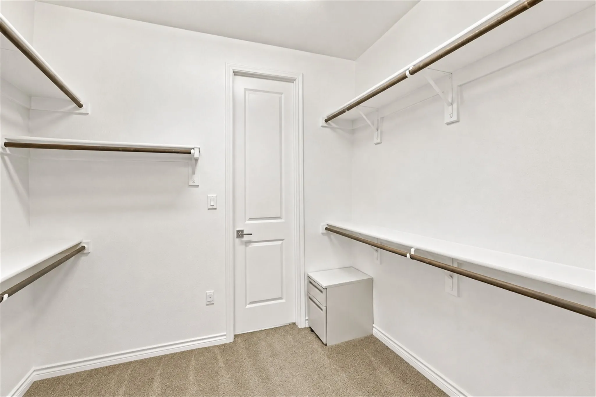 Walk-in closet with ample shelving, multiple hanging rods, and carpet flooring