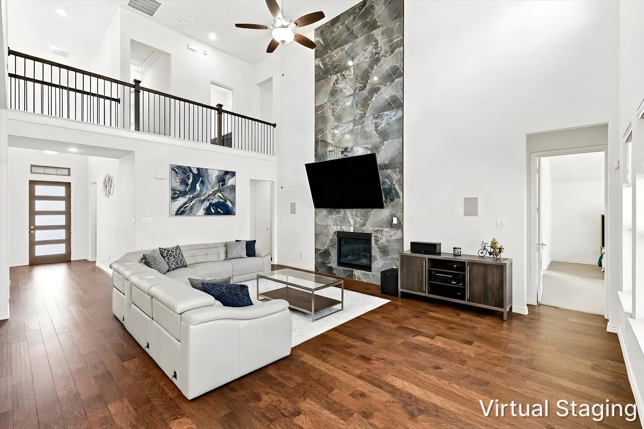 Hardwood flooring and a two-story ceiling with a ceiling fan