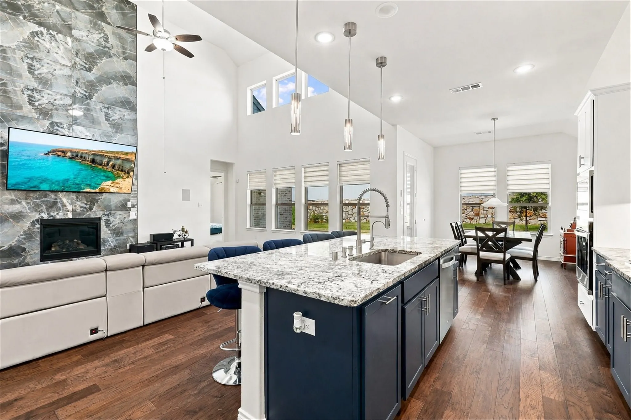 Expansive living area with vaulted ceilings, a floor-to-ceiling stone-clad fireplace, and multiple windows