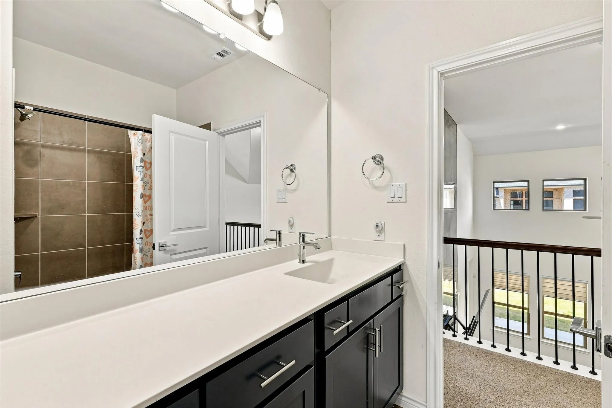 Modern bathroom vanity with a long white countertop, dark cabinetry, and dual sinks