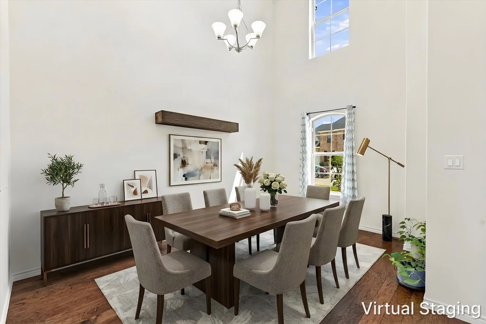 Soaring ceilings with a decorative chandelier, rich wood-finish flooring, and a transom window