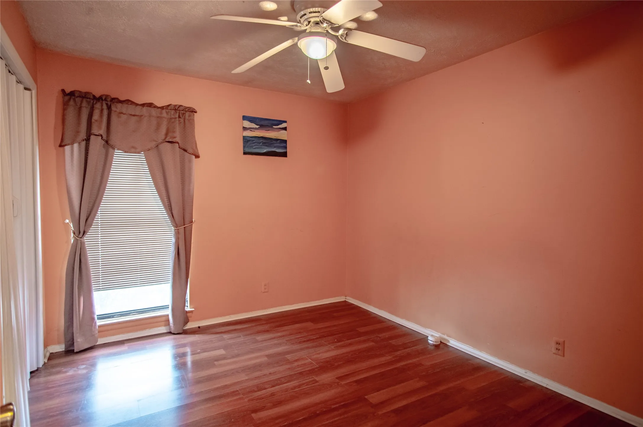 Luxury vinyl plank with base molding, ceiling fan with integrated lighting, and a window with horizontal blinds