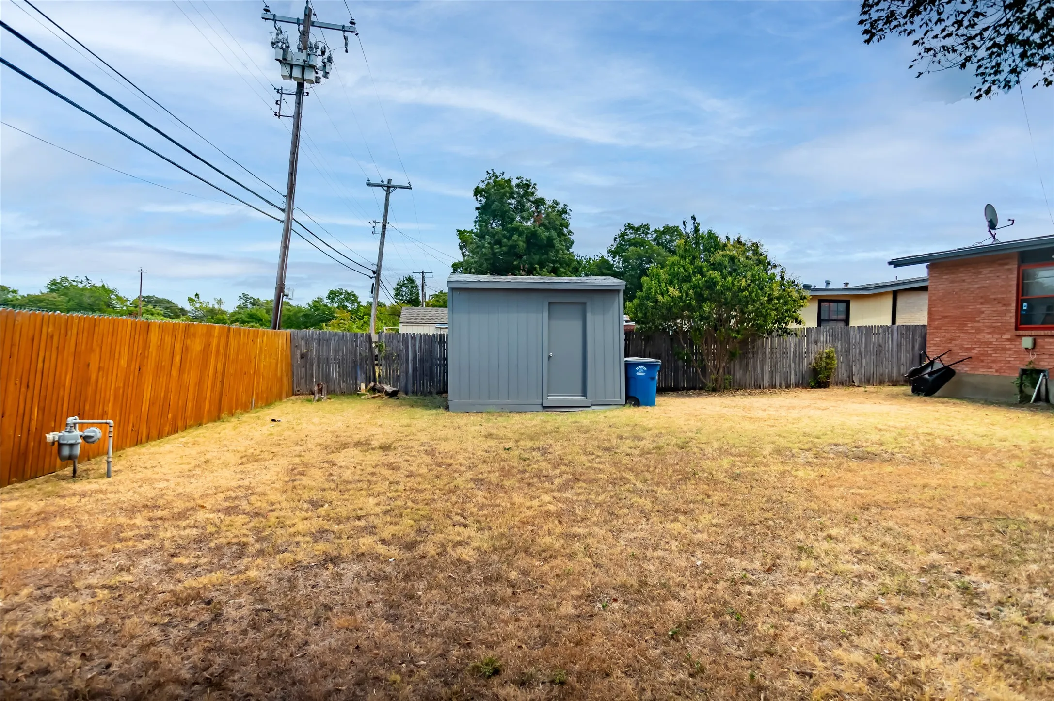 Expansive backyard featuring a wood privacy fence and a detached storage shed