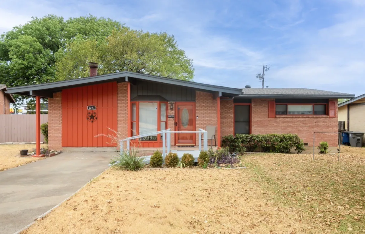 Brick exterior with an extended carport, covered porch with handrails, and a front entry door with a decorative glass insert