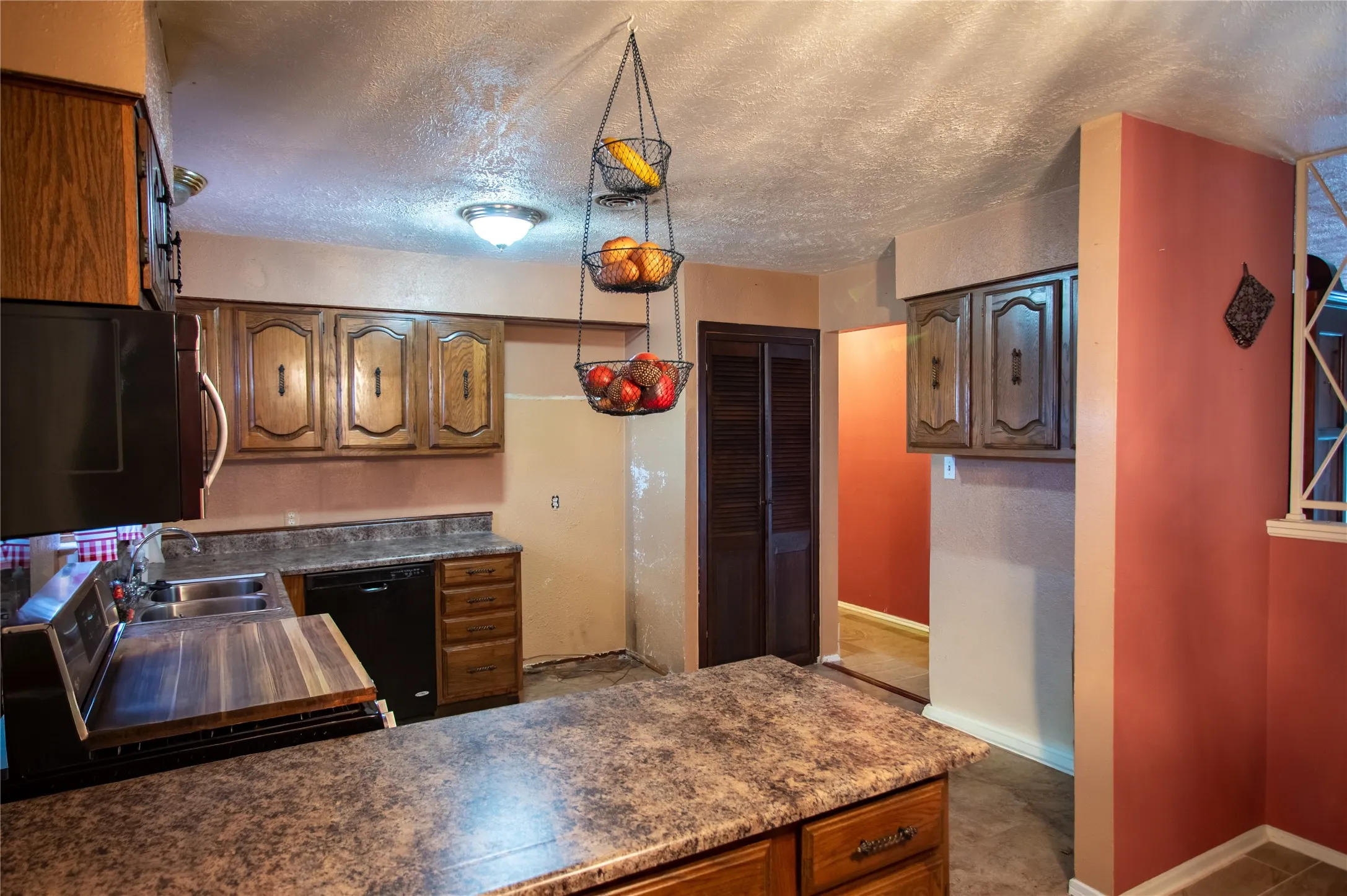 Kitchen featuring wood cabinetry, laminate countertops, a double basin stainless steel sink, and a built-in dishwasher
