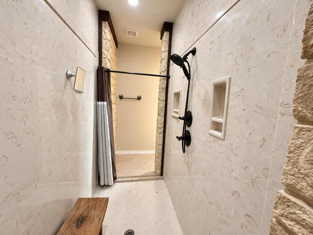Walk-in shower with tile finishes and a handheld shower fixture.
