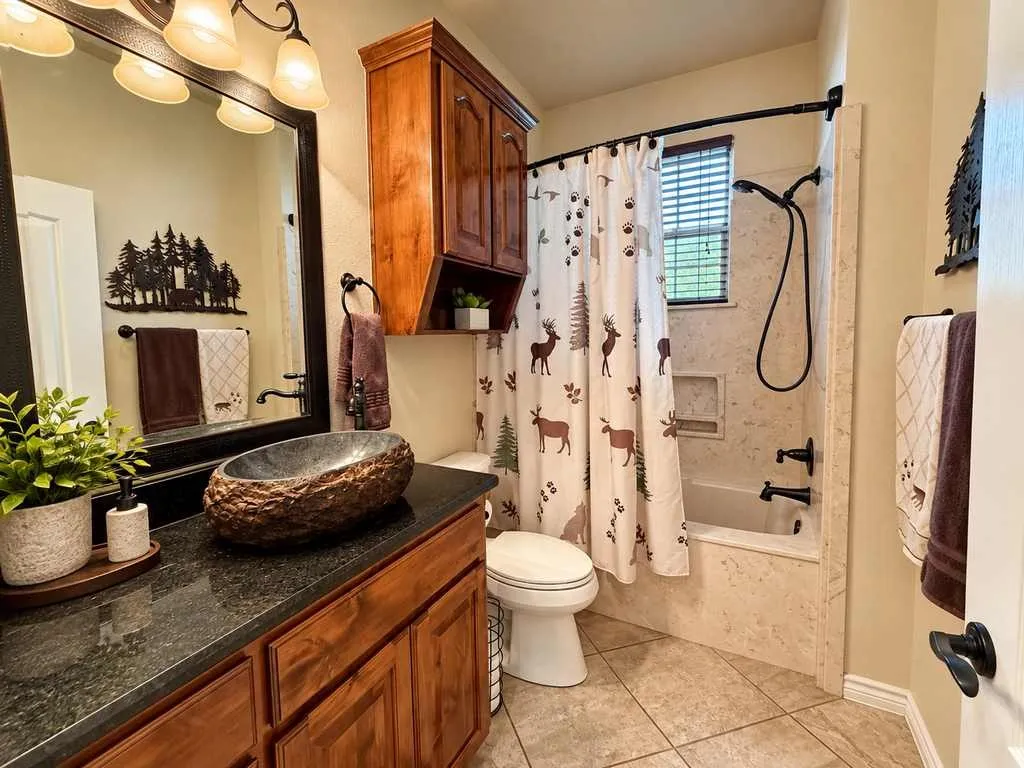 Bathroom with granite vanity, wood cabinetry and a tub/shower combination.