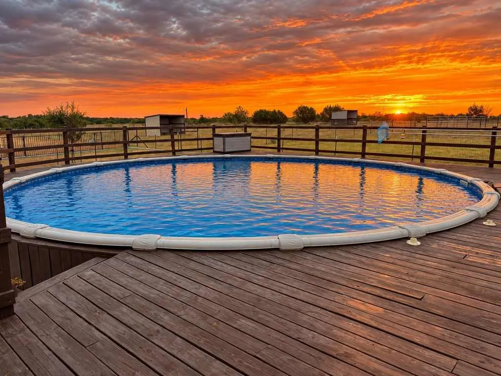 Pool and surrounding deck overlook the sunset and open pasture.