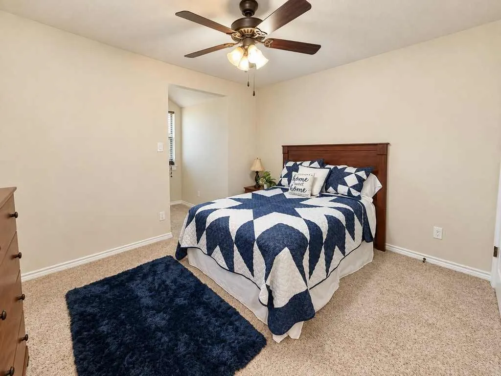 Additional bedroom with a ceiling fan and comfortable furniture space.