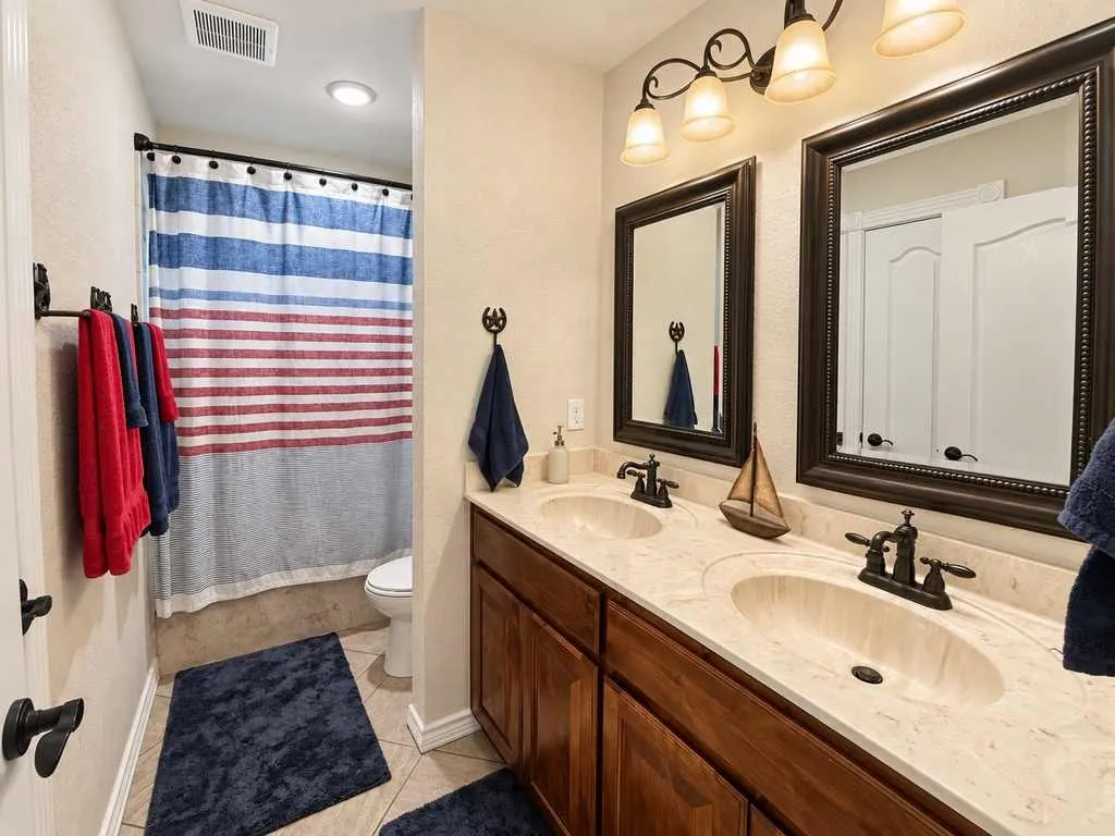 Bathroom with a long granite vanity and tub/shower combination.