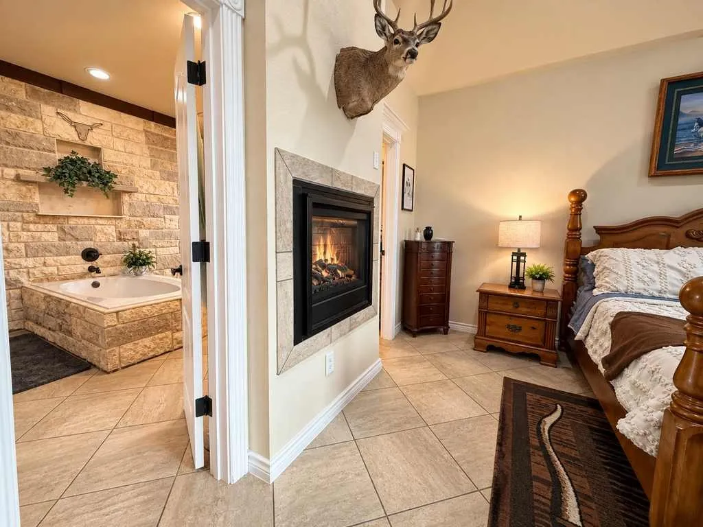 Primary suite connects to a bath with stone detailing and a shared fireplace.