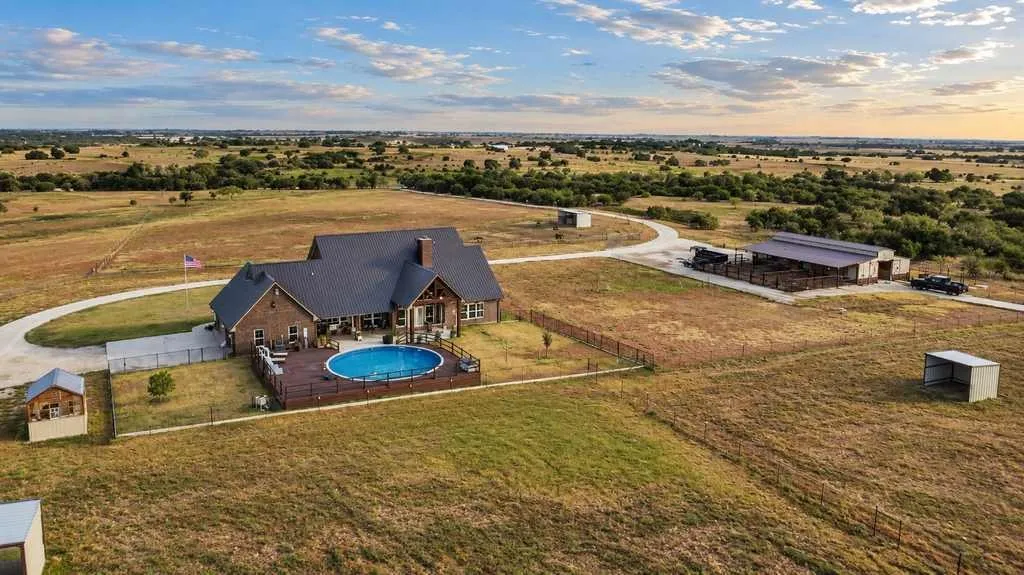 Aerial perspective showing the home, pool, outbuildings and surrounding pasture.
