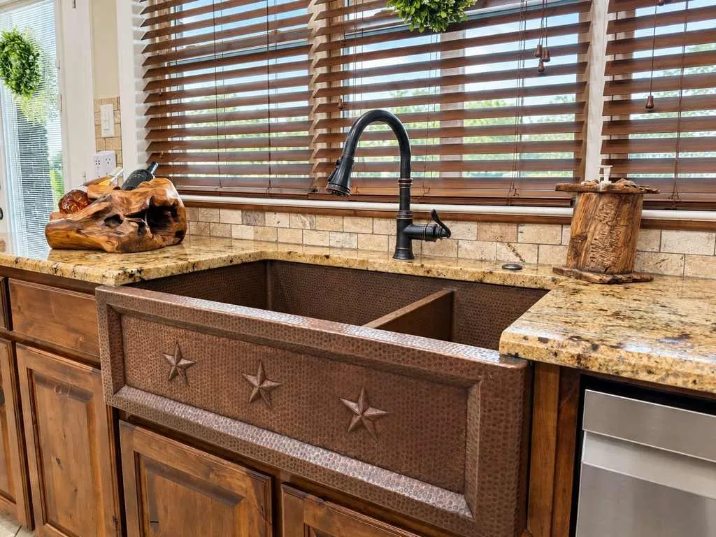Farmhouse-style sink beneath a window with granite counters and wood cabinetry.