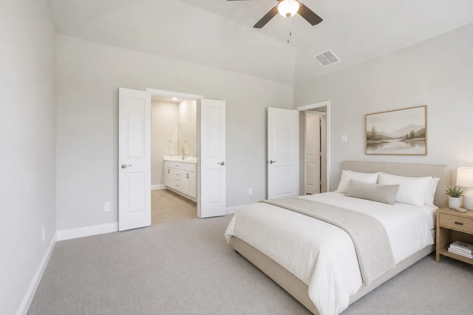 Vaulted ceiling with a ceiling fan, light gray wall paint, light gray carpet, white double doors, and a bathroom vanity with a double sink