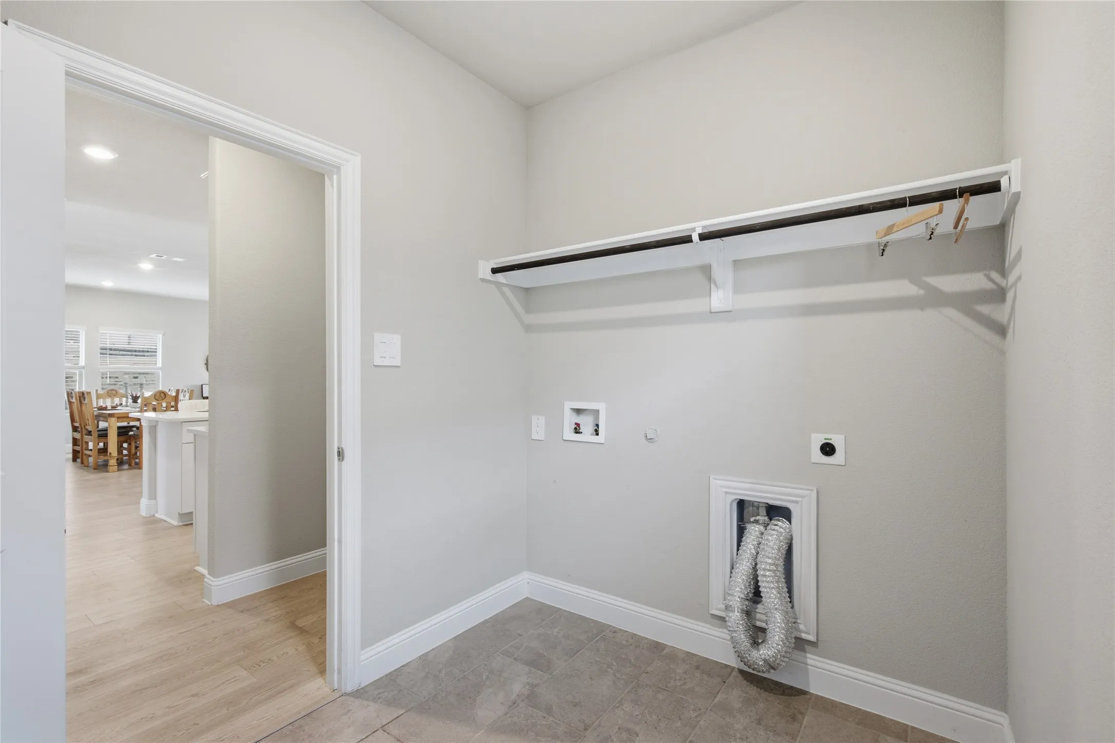 Utility room with light gray wall paint, built-in shelving, and tile flooring