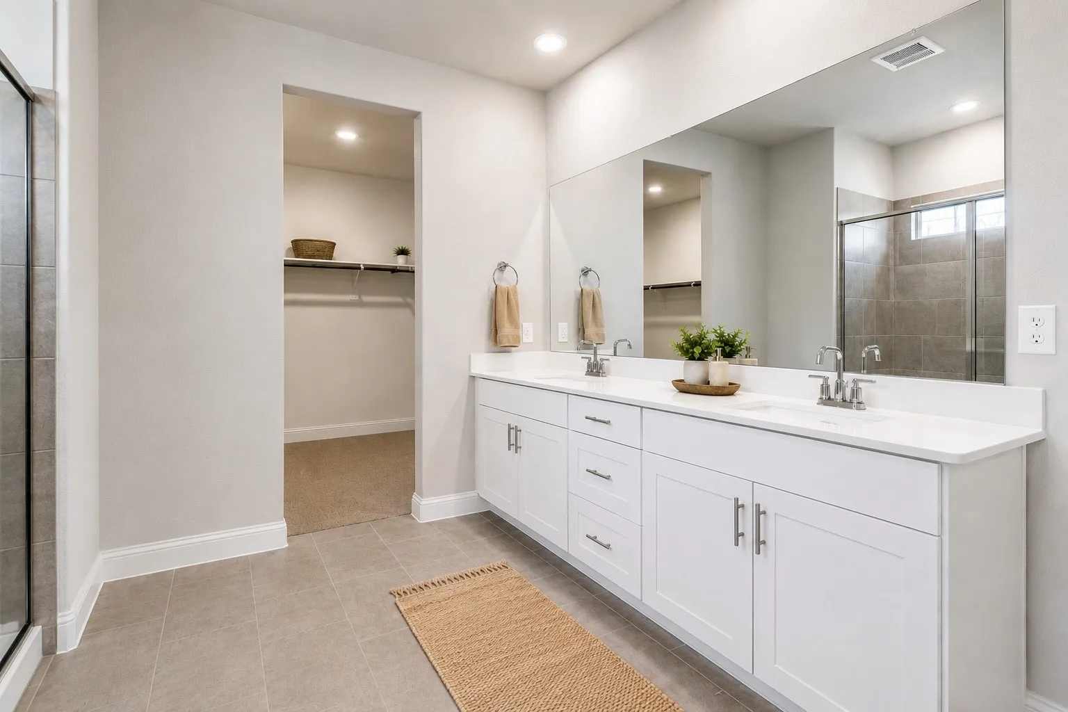 Spacious vanity with dual sinks, white cabinetry, and a large mirror