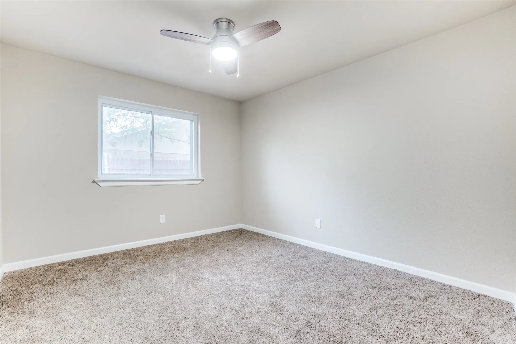 Neutral wall color, ceiling fan with light fixture, carpeted flooring, and a large window