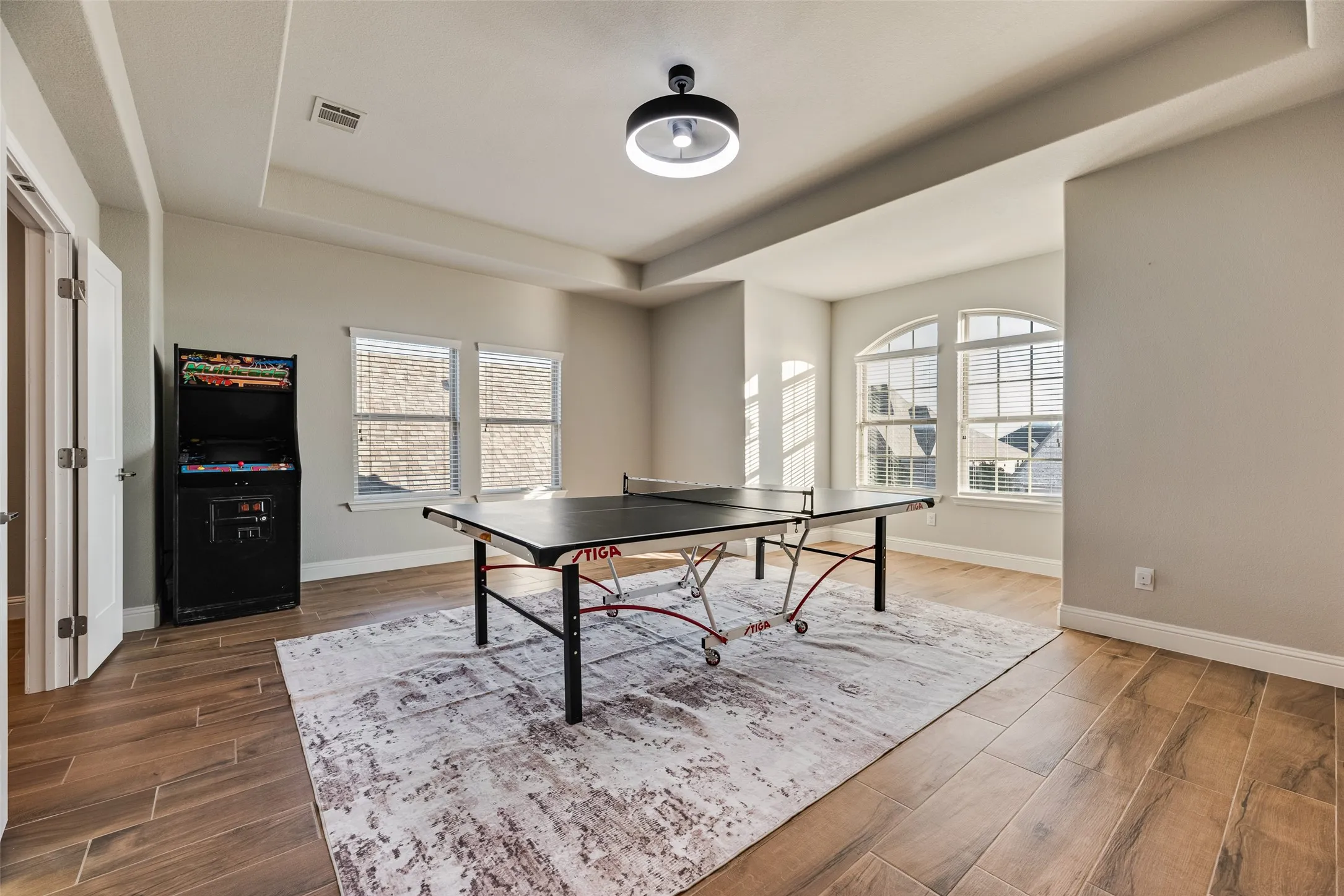 Wood-finish flooring throughout, featuring a tray ceiling with a modern flush-mount light fixture