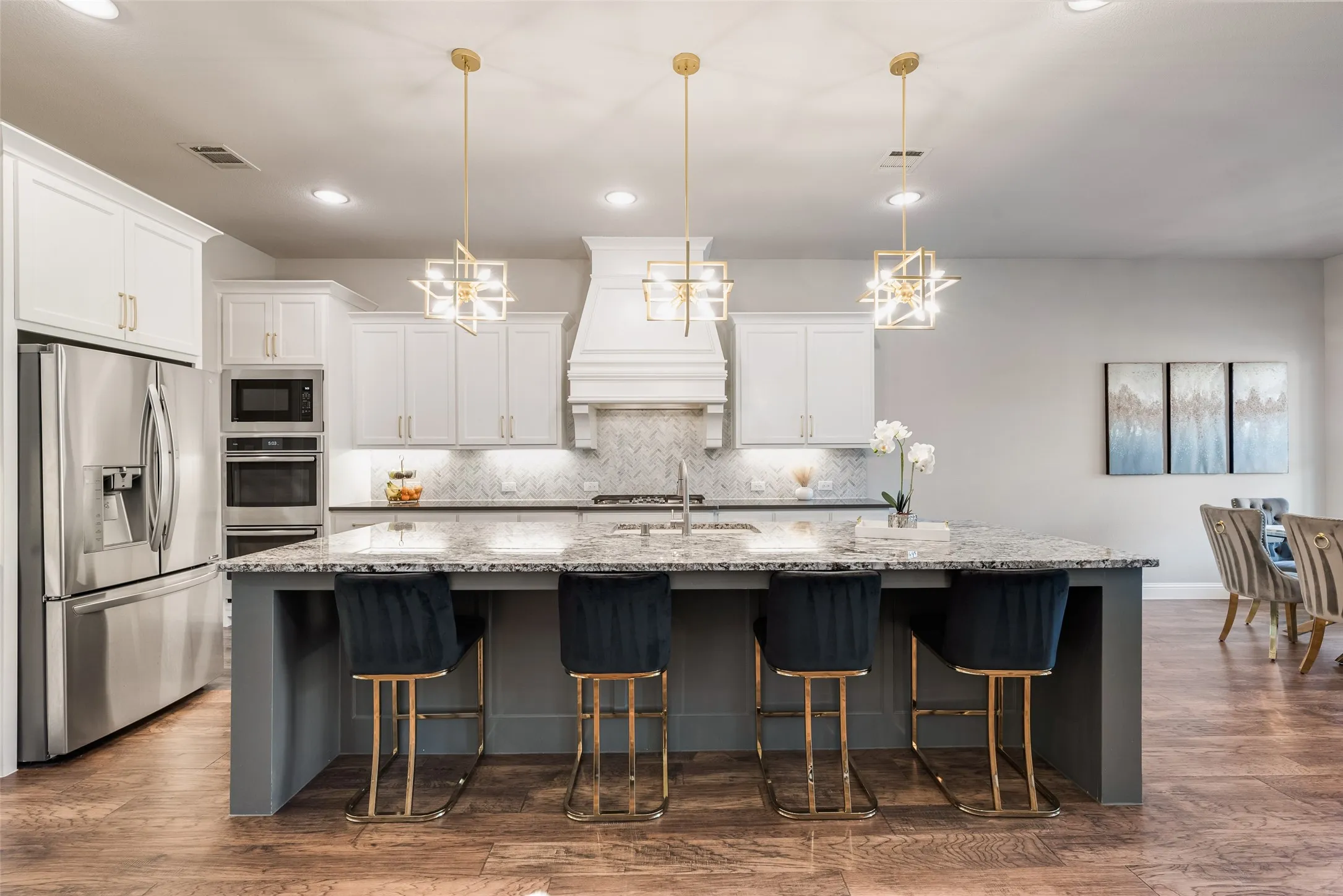 Kitchen featuring white cabinetry, stainless steel appliances, a large island with a stone countertop, and pendant lighting