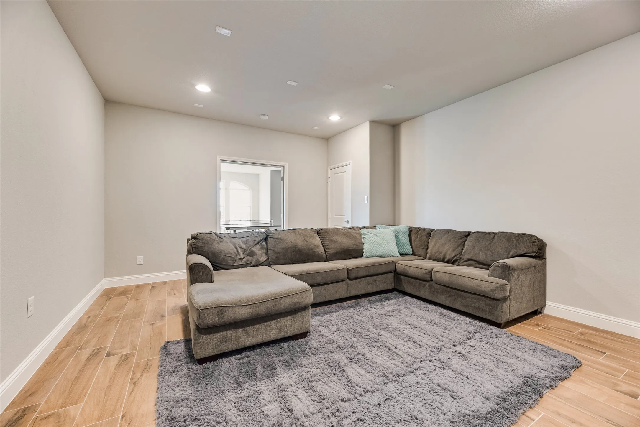 Recessed lighting, wood-finish flooring, and light-toned walls