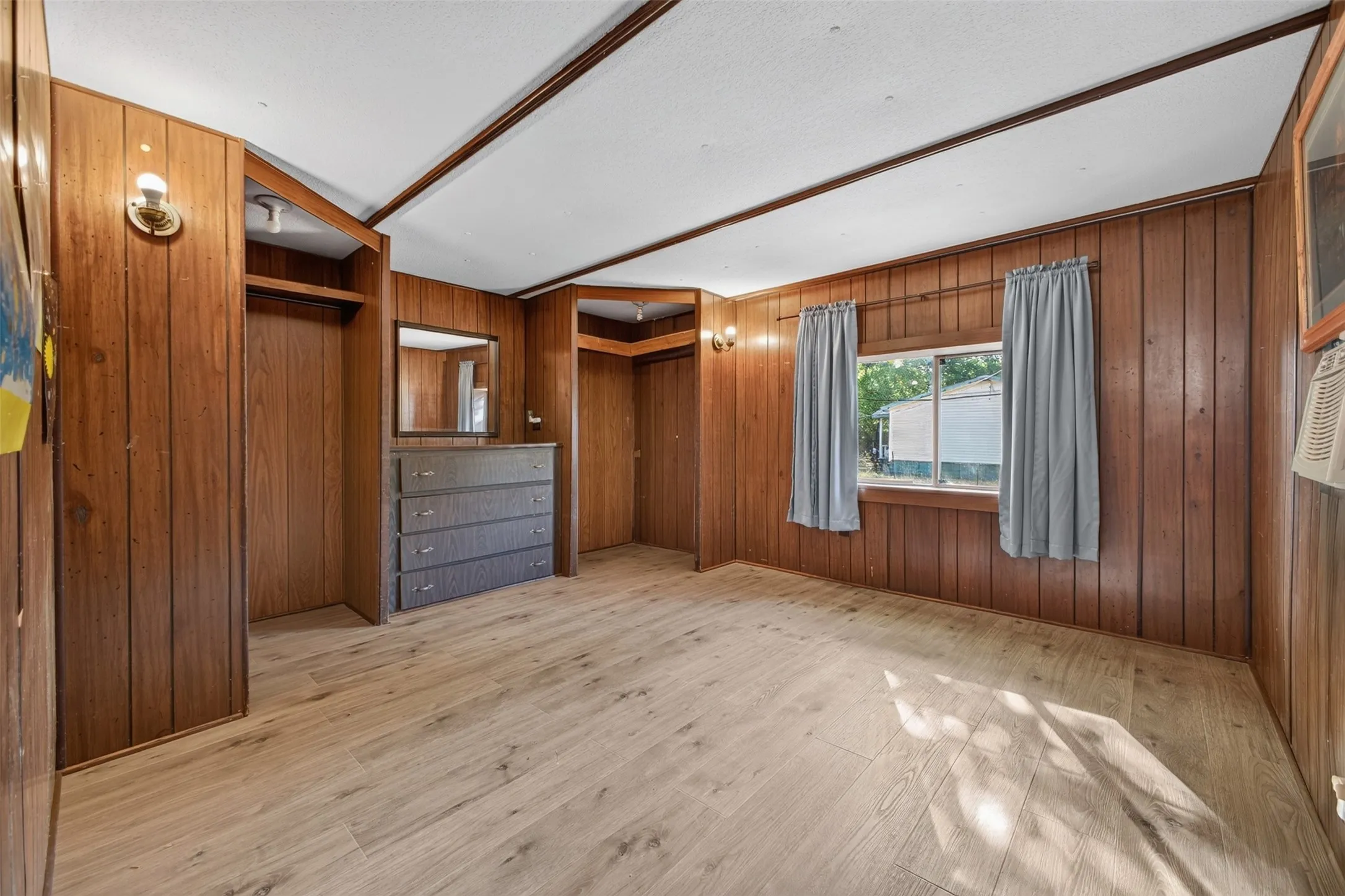 Wood-finish flooring, wood-paneled walls, built-in shelving, multiple windows, and overhead lighting