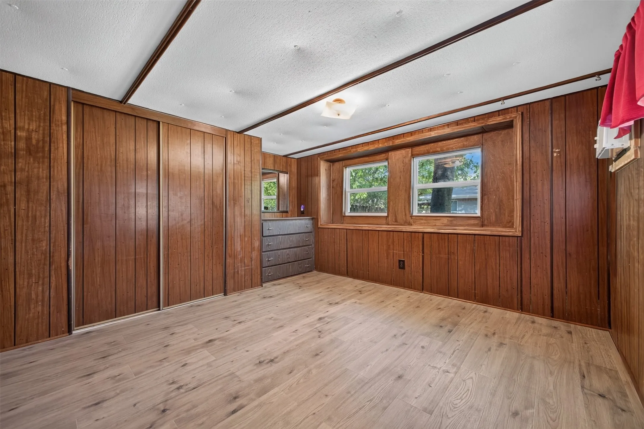 Wood-finish wall paneling, light wood-finish flooring, dual windows, and ceiling-mounted light fixture
