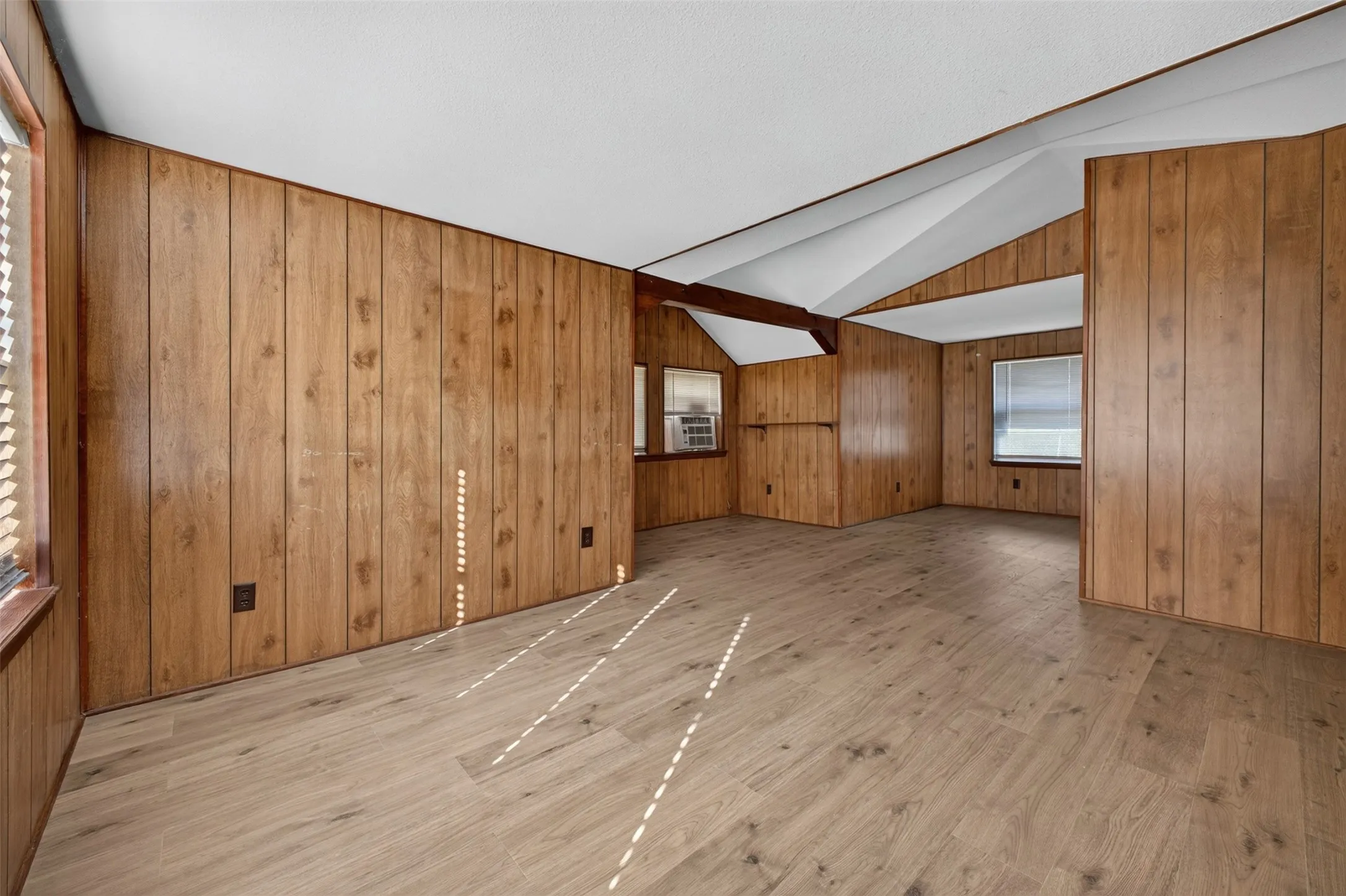 Wood-finish plank flooring, wood-paneled walls, and multiple windows