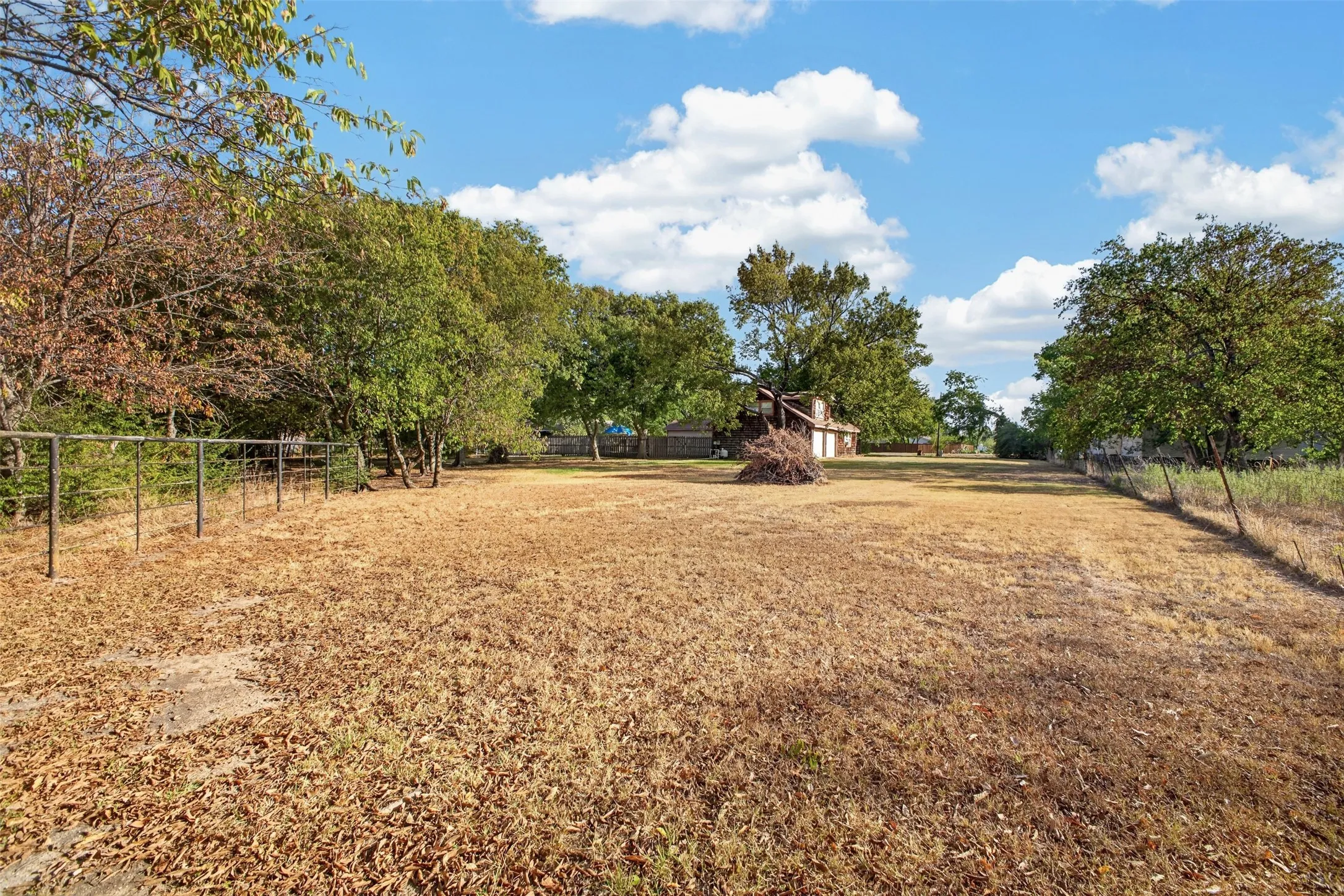 Expansive open lot with mature trees and perimeter fencing