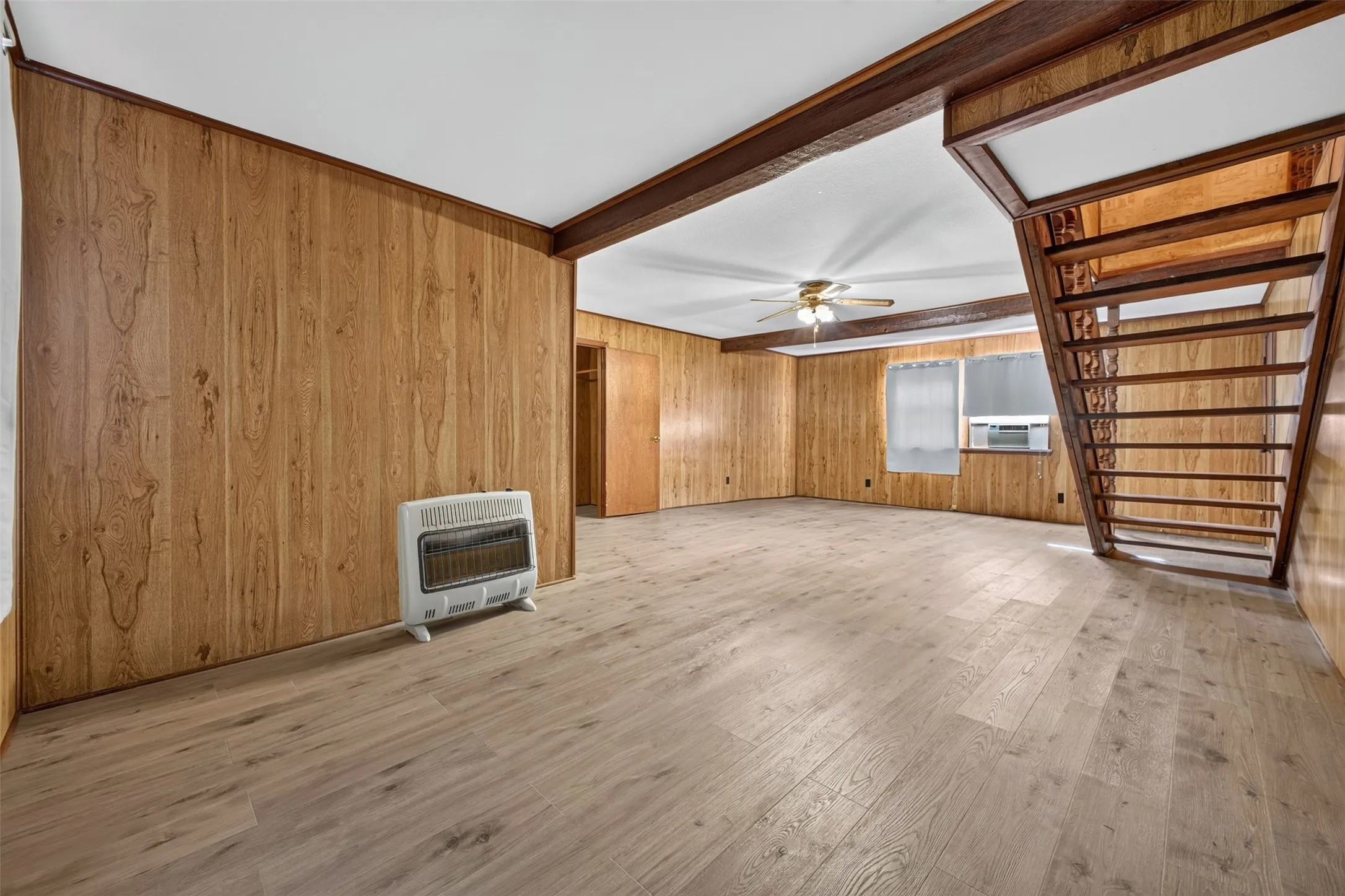 Wood-finish flooring with wood paneling walls and exposed ceiling beams
