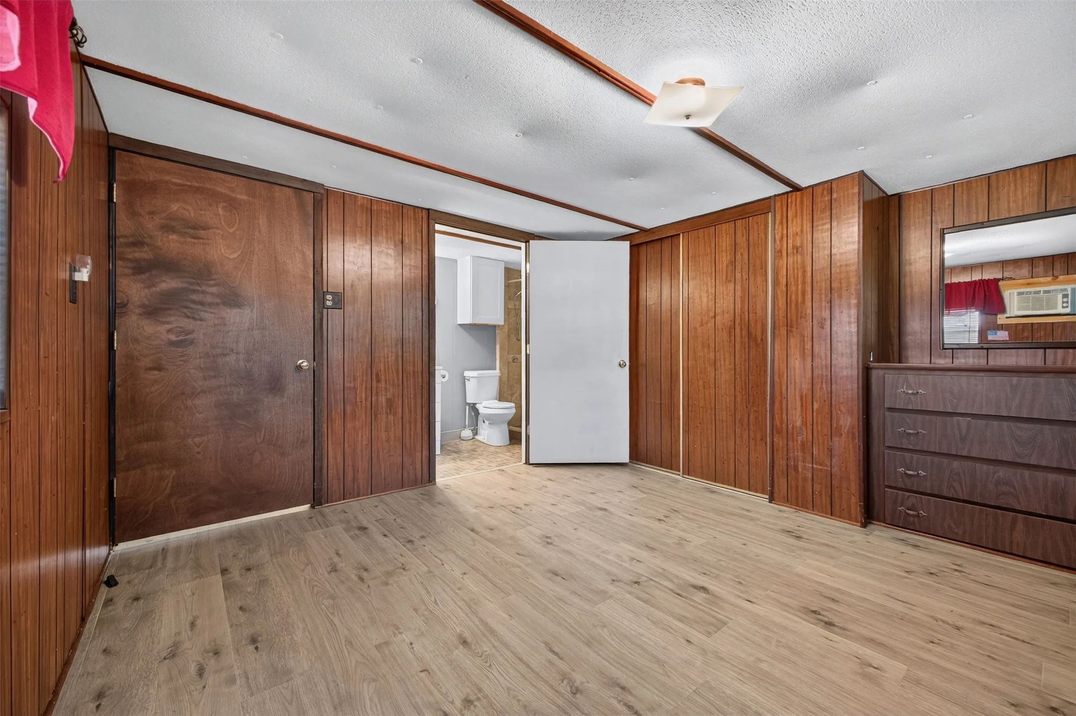 Wood-finish flooring, wood paneling, sliding closet doors, ceiling light fixture, and a white ceiling