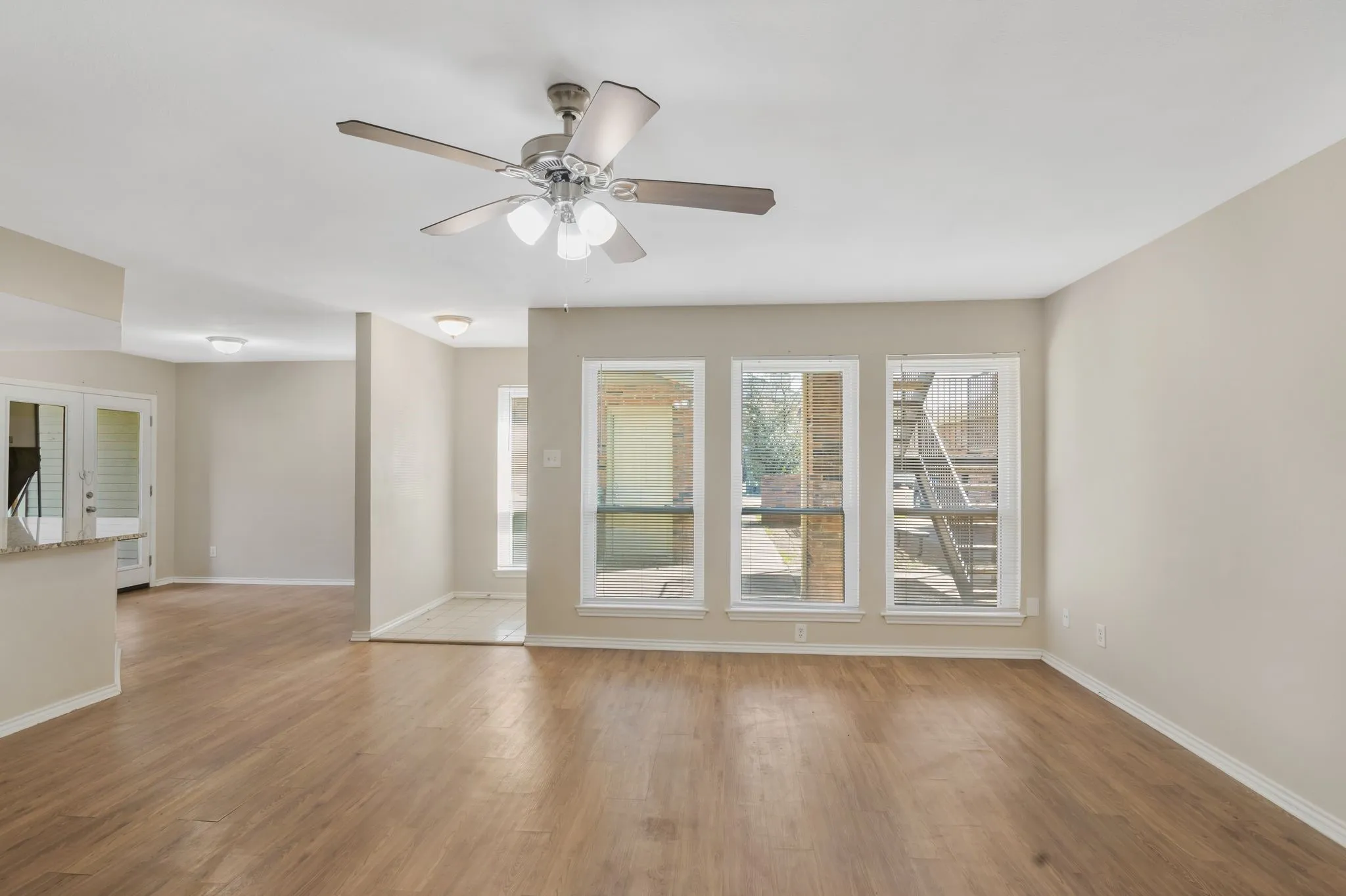 Unit B -Expansive living area with wood-finish flooring, neutral wall tones, and abundant natural light from multiple windows