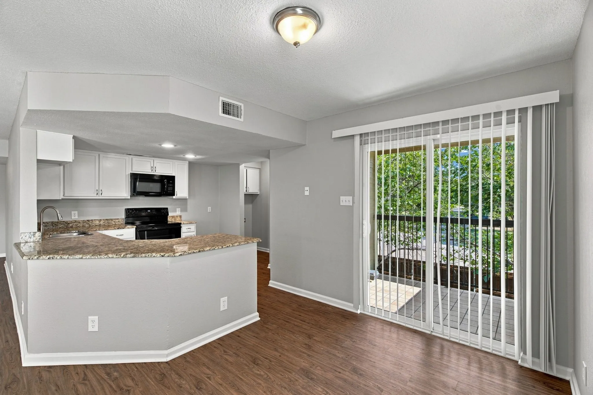 Unit D -Kitchen with white cabinetry and built-in black appliances.