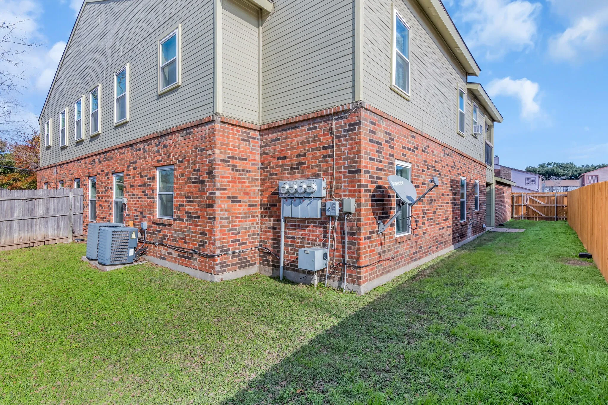 Unit A - Exterior featuring brick and siding construction, multiple windows, a manicured lawn, and a wood privacy fence