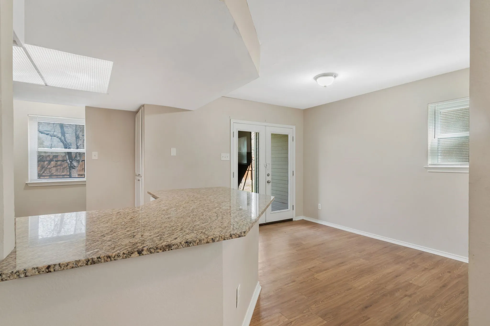Unit B -Granite-finish countertop, wood-finish flooring, two windows, and double glass-paneled doors