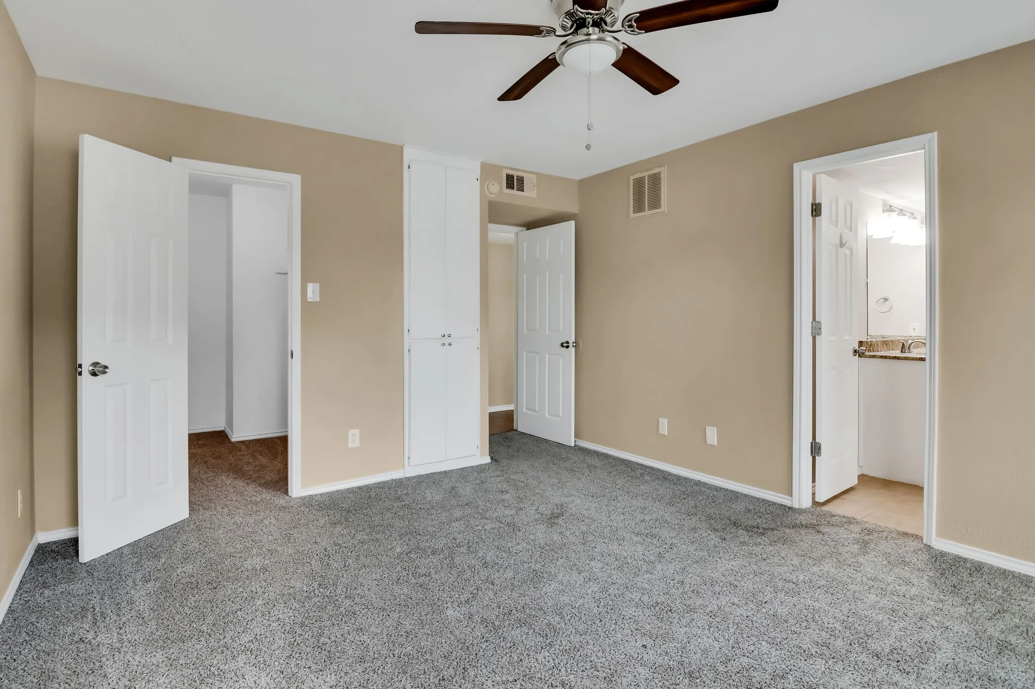Unit A - Built-in storage cabinetry, white six-panel interior doors, and a ceiling fan with light fixture