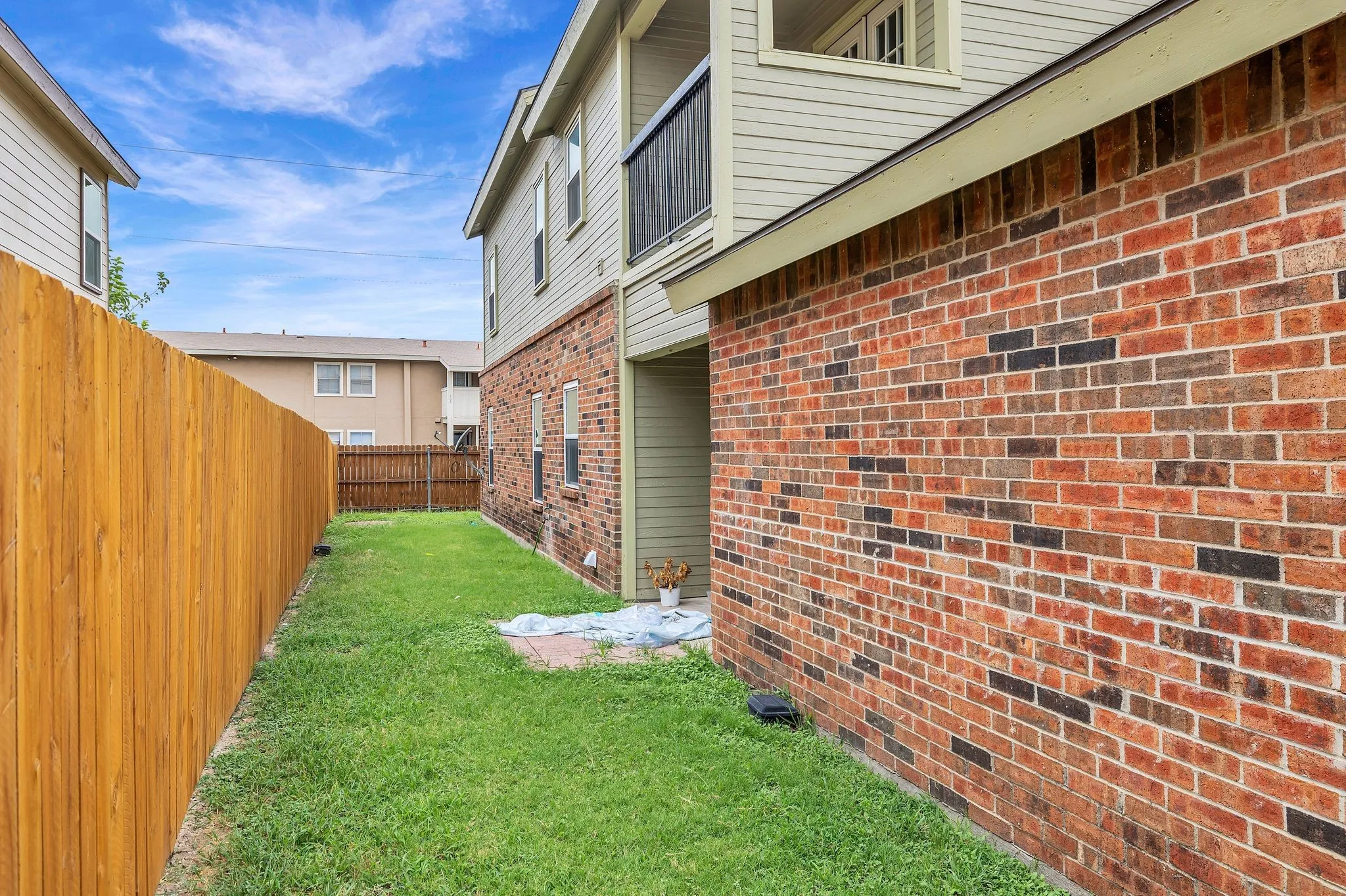 Unit C- Enclosed side yard featuring a wood privacy fence, brick exterior, and a second-story balcony