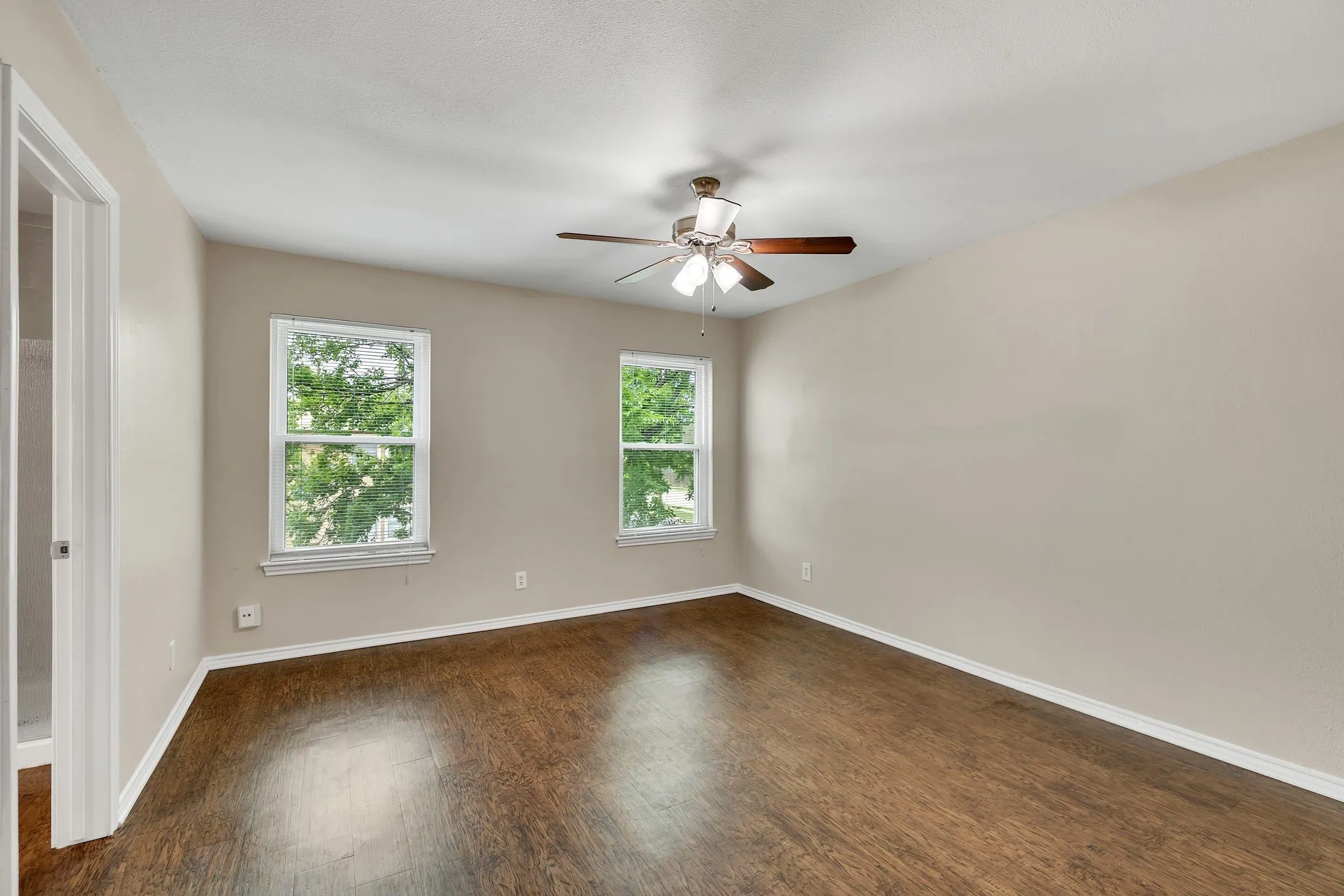 Unit C- Wood-finish flooring, two windows, and a ceiling fan with integrated lighting