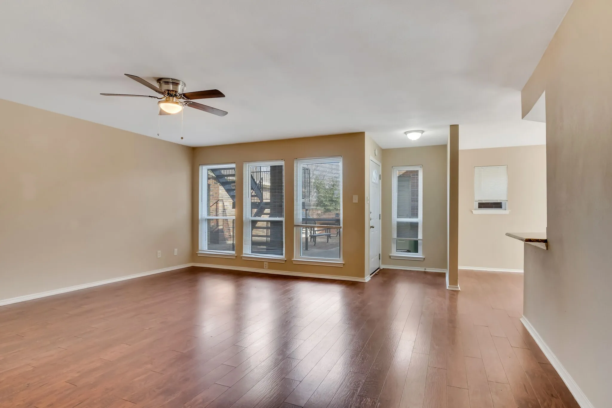 Unit A - Spacious room featuring wood-finish flooring, a ceiling fan with integrated lighting, and multiple windows