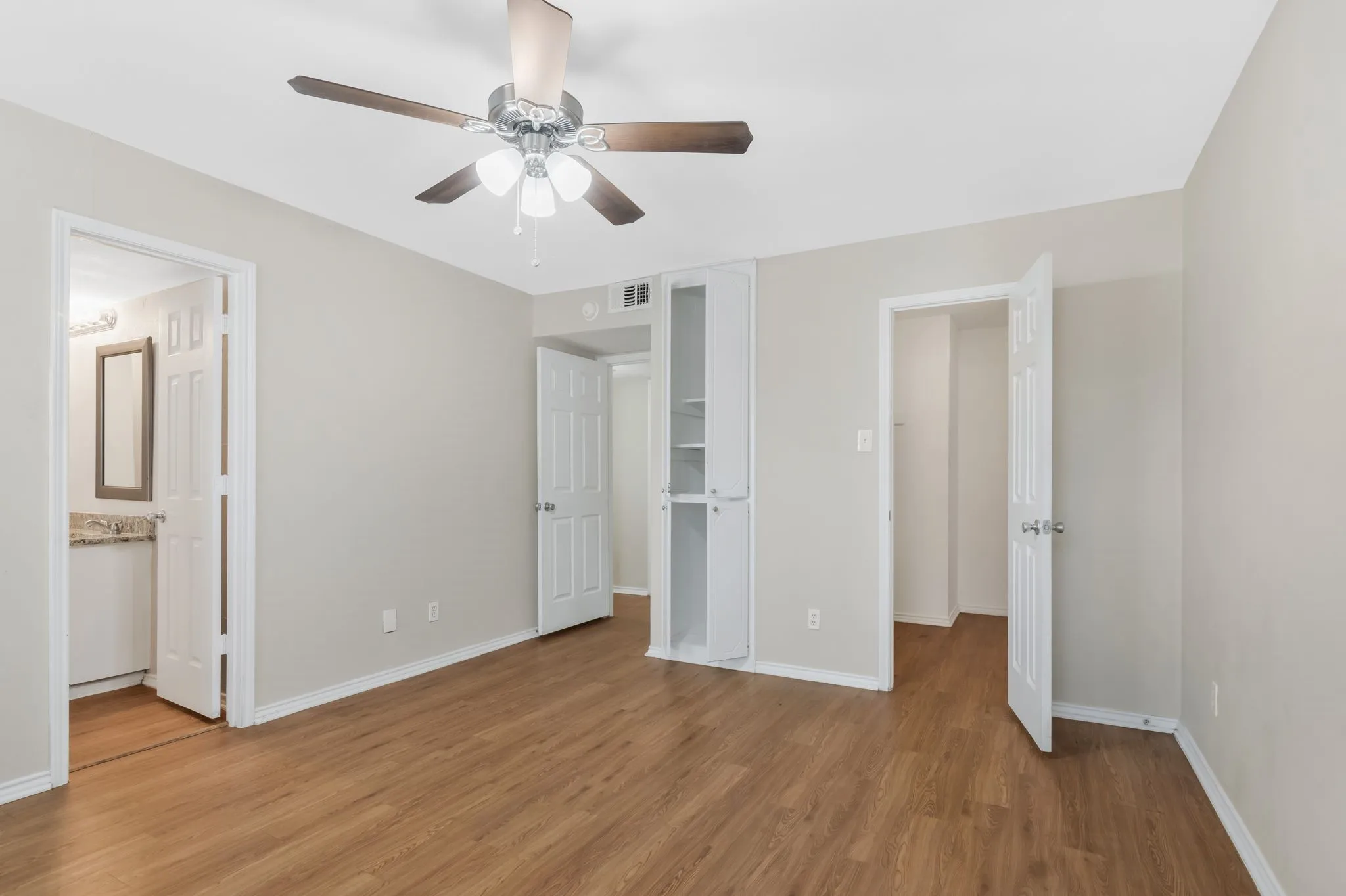 Unit B - Wood-finish flooring, ceiling fan with integrated lighting, built-in shelving, white paneled doors, and light-toned wall finishes