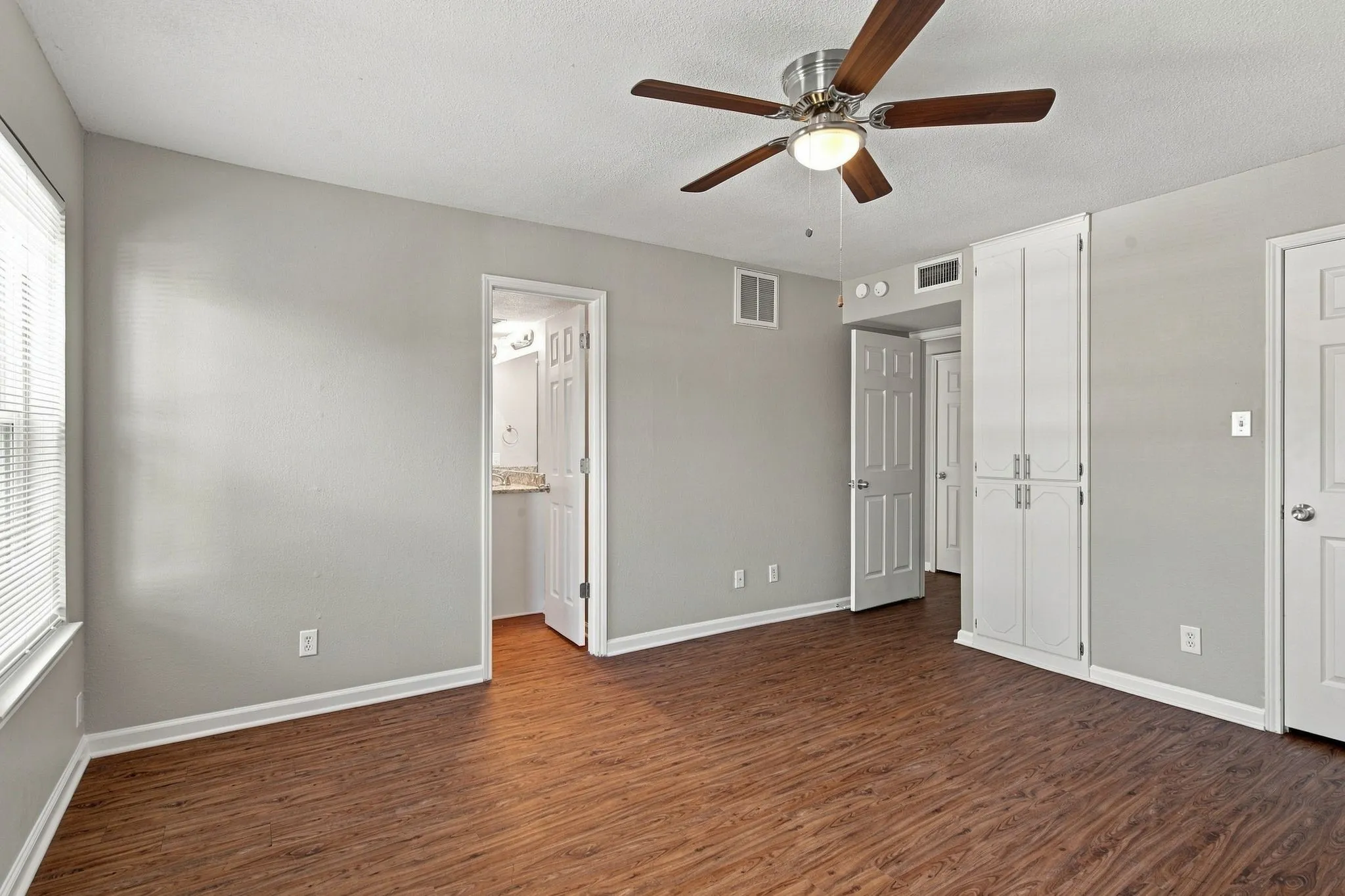 Unit D -Wood-finish flooring, ceiling fan with integrated lighting, built-in white cabinetry, window with blinds, and white interior doors