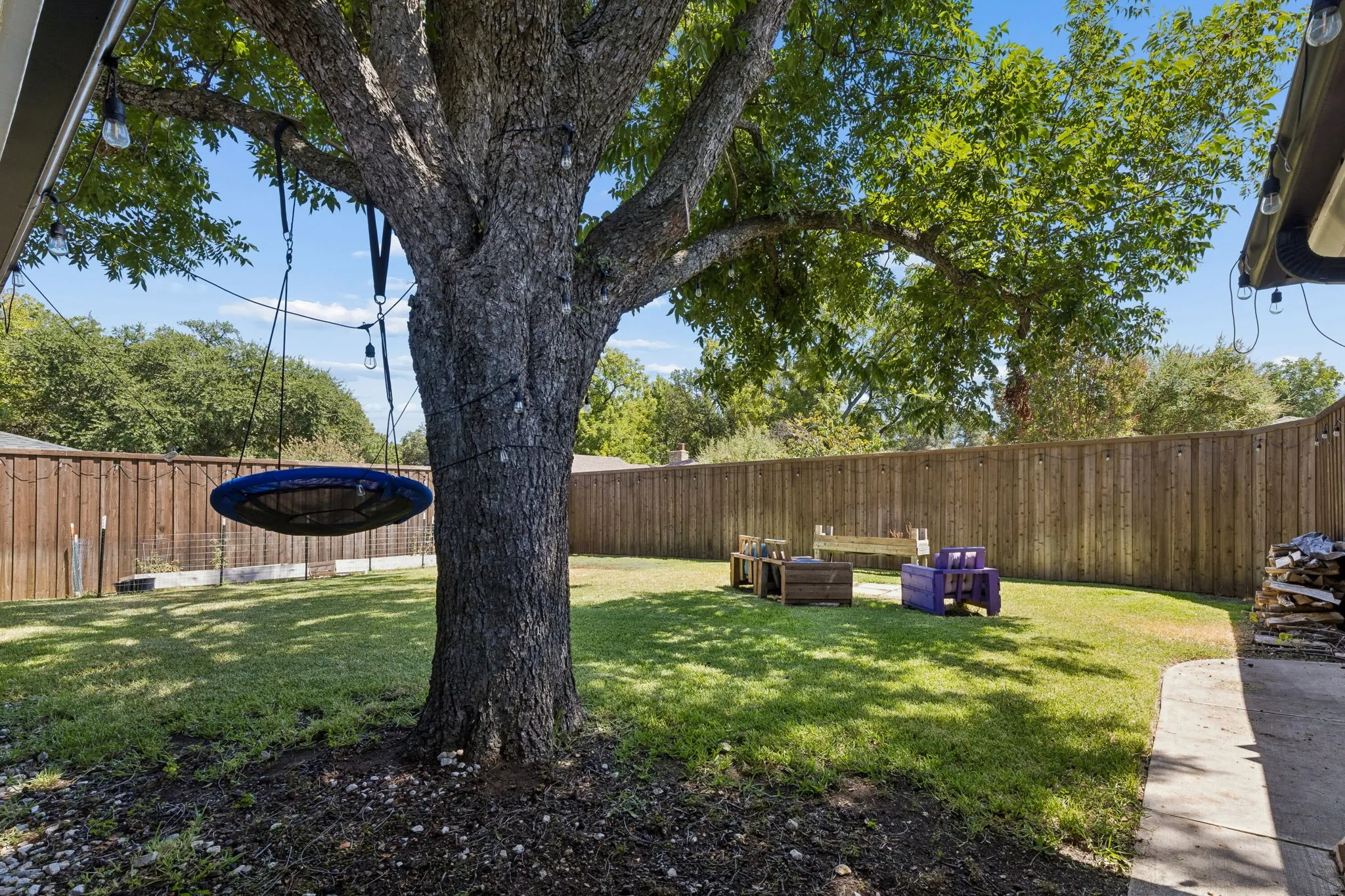 Spacious backyard featuring a substantial mature tree, a manicured lawn area, and a privacy fence