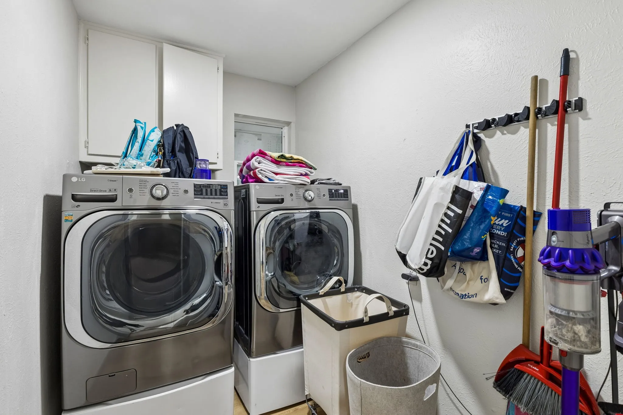 Laundry area featuring a side-by-side washer and dryer, upper cabinetry, and a window