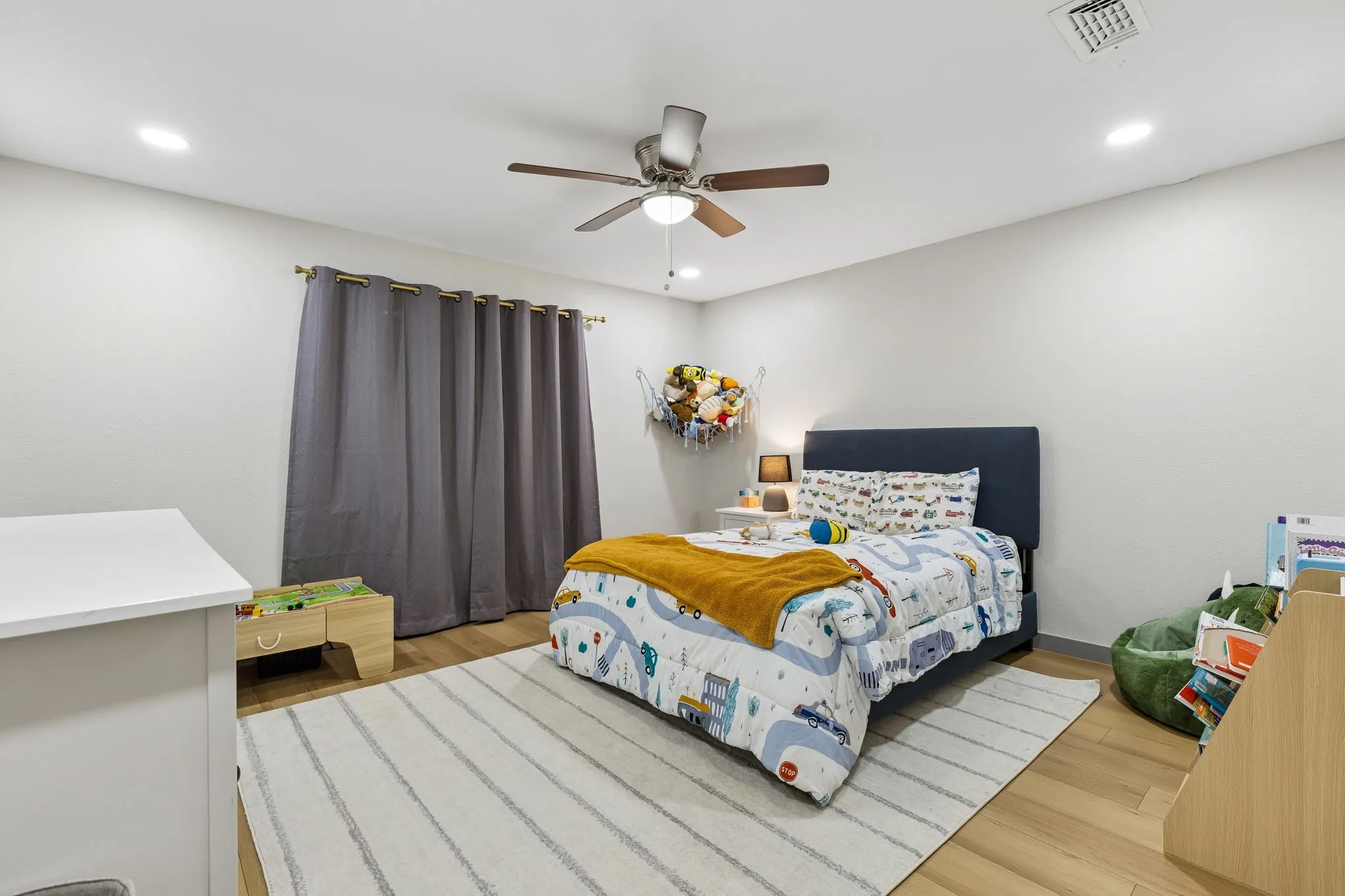 Recessed ceiling lighting, ceiling fan with light, wood-finish flooring, and a window with curtain rod