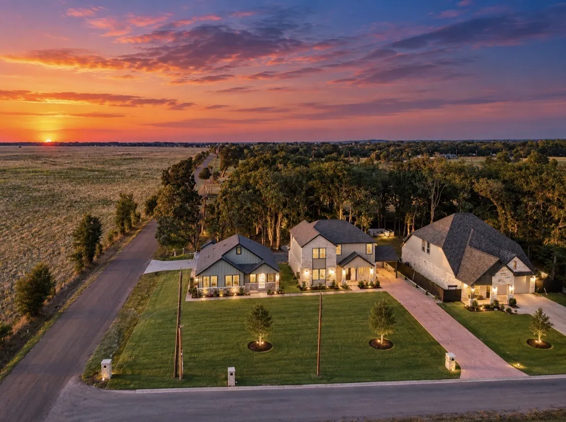 Aerial perspective showcasing multiple homes with varied architectural styles, expansive green lawns, and long driveways